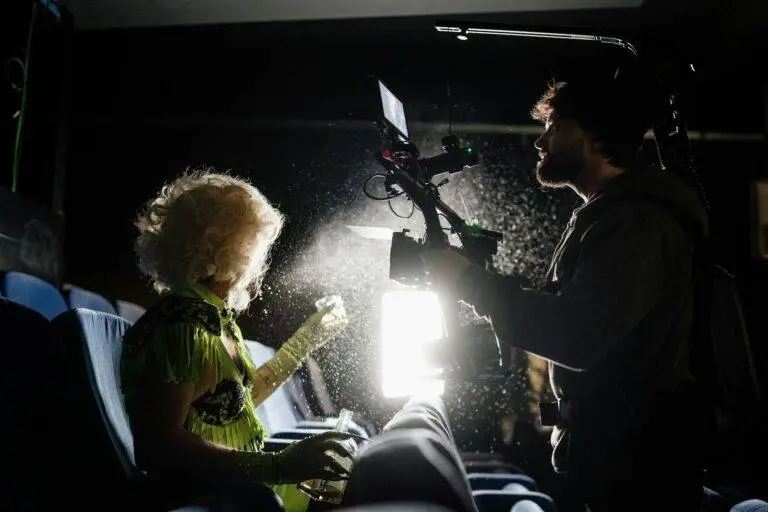 Filmmaker capturing a scene in a dimly lit theater with dramatic lighting effects.