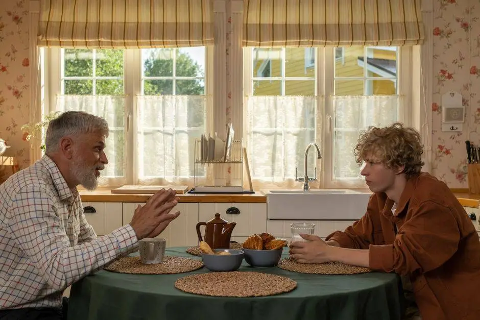 Elderly man and teenage boy enjoying breakfast and conversation at a table.