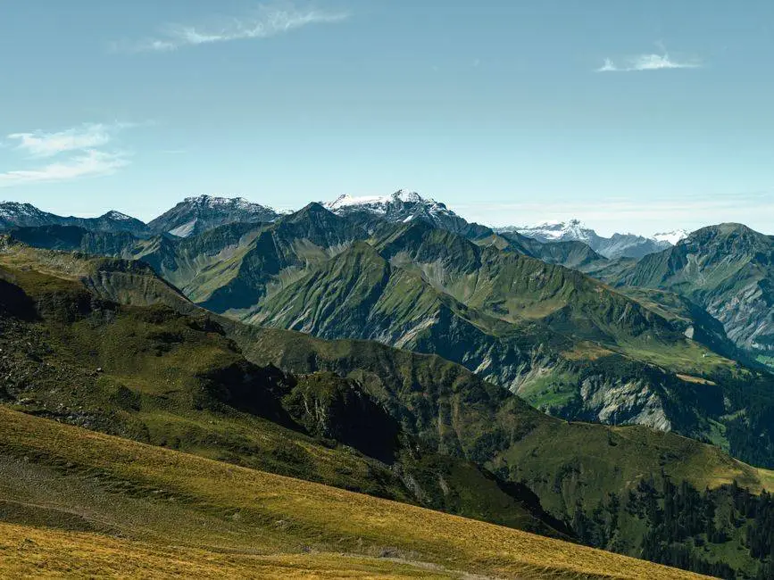 Panoramic view of the stunning Swiss Alps with lush greenery and snow-capped peaks.